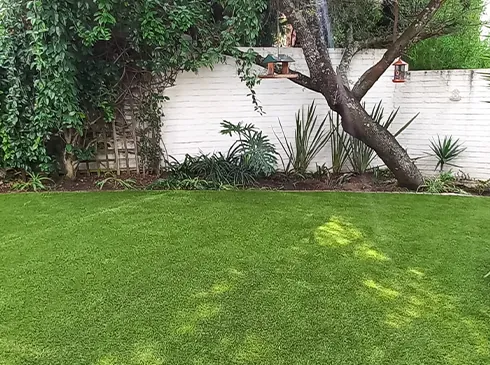 A compact garden with artificial grass and a white boundary wall