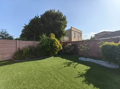 A finished artificial grass garden with a curved planting border